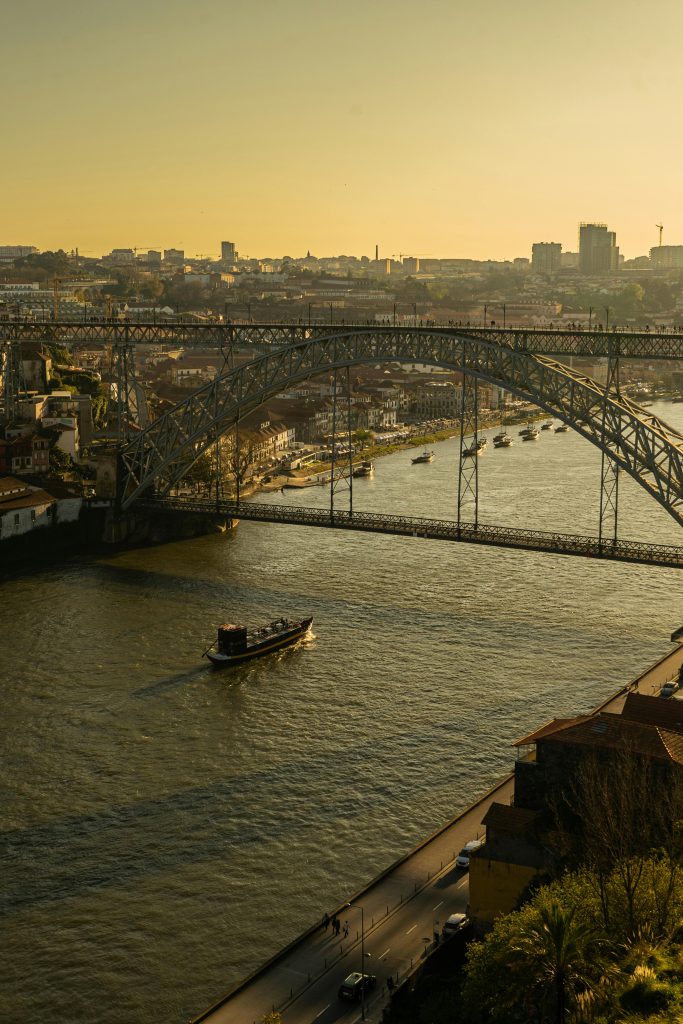 Aerial view of Porto featuring the iconic Dom Luís I Bridge over the Douro River at sunset.