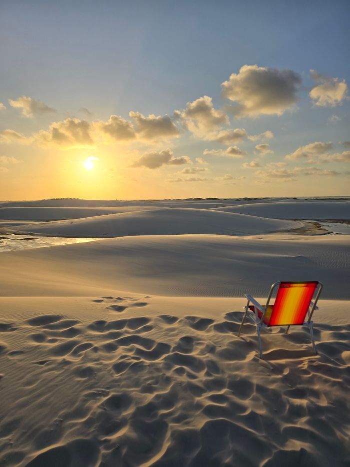 Atins Brazil A colorful chair faces a tranquil sunset over the stunning sand dunes in Maranhão, Brazil.