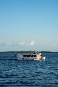 A boat sailing on the Rio Negro under a clear sky in Manaus, Amazonas.